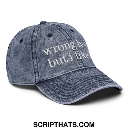 A faded blue denim unstructured dad hat with white embroidered text wrong hole but i like it